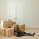 Person in Black Leather Boots Sitting on Brown Cardboard Boxes