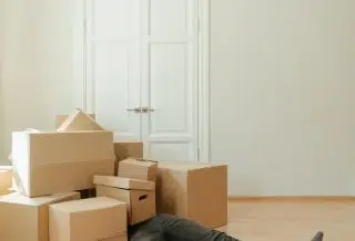 Person in Black Leather Boots Sitting on Brown Cardboard Boxes