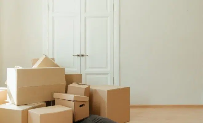 Person in Black Leather Boots Sitting on Brown Cardboard Boxes